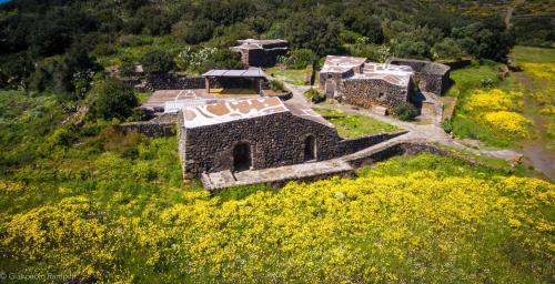 an old stone building in a field of yellow flowers at 2 Gatti - Sogno in Pantelleria