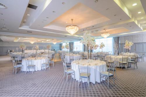 a banquet hall with white tables and chairs and chandeliers at Shearwater Hotel & Spa in Ballinasloe
