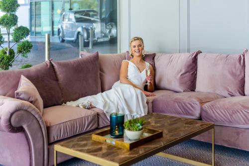 a woman sitting on a purple couch holding a bottle at Shearwater Hotel & Spa in Ballinasloe