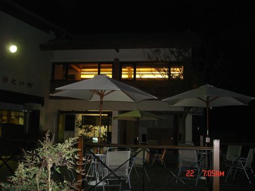 three tables with umbrellas in front of a building at night at Pear Story House in Dongshi