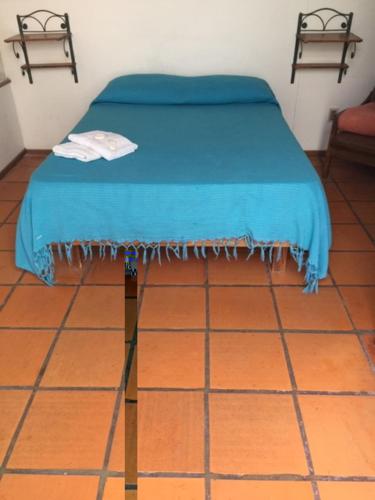 Una cama con una manta azul en el suelo en Hostel El Español, en Colonia del Sacramento