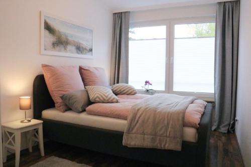 a bed with pillows and a window in a room at Ferienwohnung Sandwig in Glücksburg