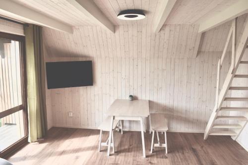 a white table and chairs in a room with a tv at Retro chaty Soběšky in Horní Soběšovice