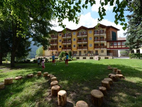 a group of people in a park with logs in the grass at Family Hotel Gran Baita in Pozza di Fassa