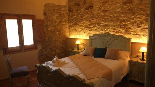 a bedroom with a large bed in a stone wall at La Masia de Montpedrós in Peralada