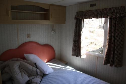 a bedroom with a bed with a red headboard and a window at lathuillere in La Motte-Saint-Jean