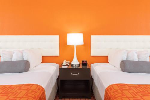 two beds in a room with an orange wall at Howard Johnson by Wyndham Rock Hill in Rock Hill