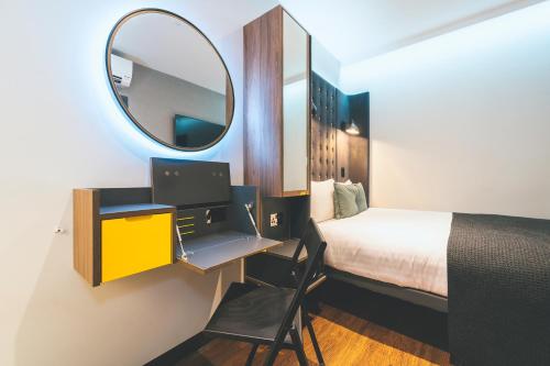 a bedroom with a bed and a mirror and a desk at Point A London Liverpool Street in London