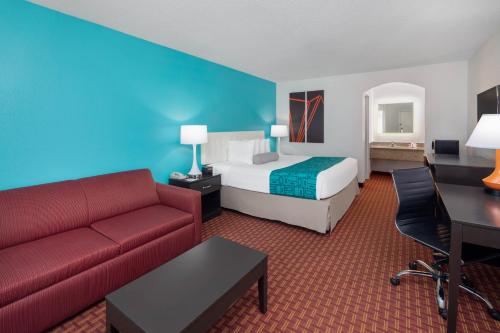 a hotel room with a bed and a red couch at Howard Johnson by Wyndham Rock Hill in Rock Hill