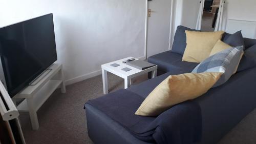 a living room with a blue couch and a flat screen tv at Red Lion in Exeter