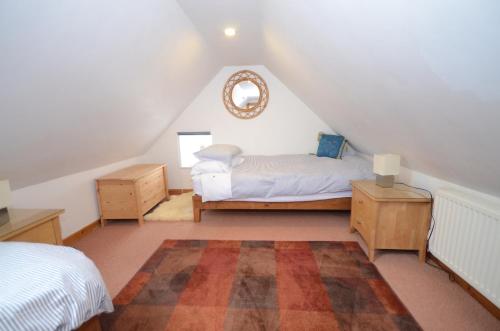 a attic bedroom with a bed and a mirror at Driftwood Cottage in Banff