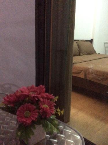 a vase of red flowers on a table in a room at Amaretto Hostel in Surat Thani