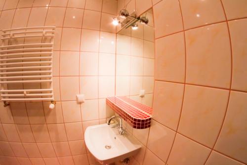 a white tiled bathroom with a sink and a mirror at Apartament Kopernik in Kraków