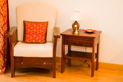 a chair and a nightstand with a lamp and a table at Apartament Kopernik in Kraków