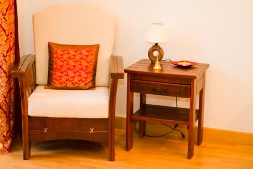 a chair and a nightstand with a lamp and a table at Apartament Kopernik in Krakow