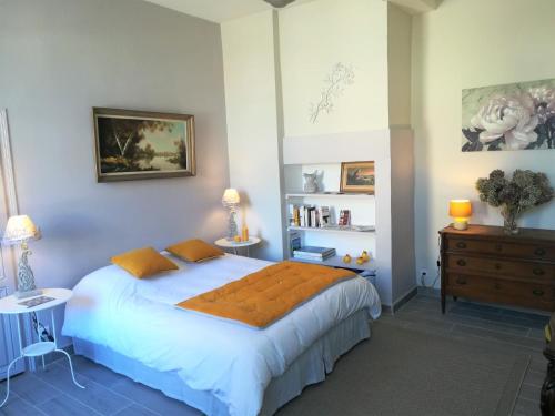 ein Schlafzimmer mit einem großen weißen Bett mit orangefarbenen Kissen in der Unterkunft Le Clos Sainte Foy in Morlaas