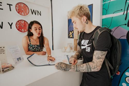 a woman standing behind a counter with a man with a tattoo at Murals Hostel and Cafe in Cebu City