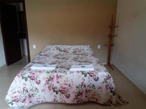 1 dormitorio con 1 cama con colcha rosada de flores en Pousada Recanto do Sossego- Serra da Canastra, en Vargem Bonita
