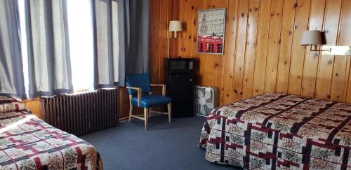 une chambre d'hôtel avec deux lits et une chaise dans l'établissement Caribou Lodge and Motel, à Soda Springs