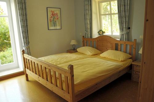 a bedroom with a wooden bed and two windows at Eschenhof in Syke