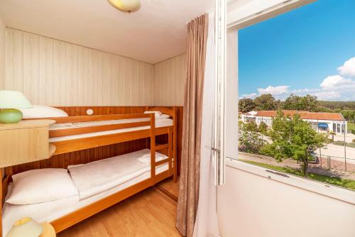 a bedroom with bunk beds and a large window at Hotel Omorika in Punat