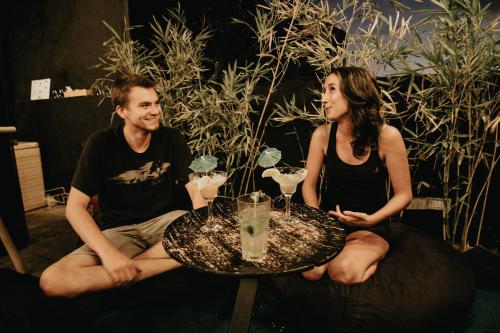 a man and woman sitting around a table with drinks at Murals Hostel and Cafe in Cebu City