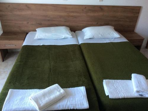 two beds in a bedroom with green sheets and pillows at Fania Apartments in Kardamaina