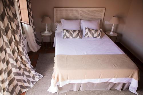 a bedroom with a large white bed with two lamps at Hotel Rural Las Tejuelas in Valdecaballeros