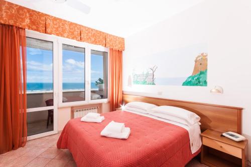 a bedroom with a red bed and a large window at Hotel Ambasciatori in Marina di Pietrasanta