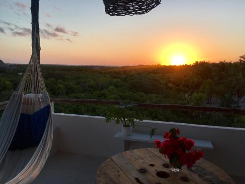 a hammock on a balcony with a sunset in the background at LunArena Barefoot Comfort in El Cuyo