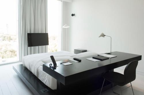 1 dormitorio con escritorio, cama y ventana en Habita Monterrey, a Member of Design Hotels, en Monterrey