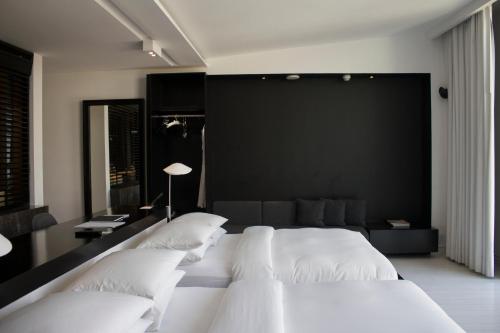 a bedroom with white beds and a black wall at Habita Monterrey, a Member of Design Hotels in Monterrey