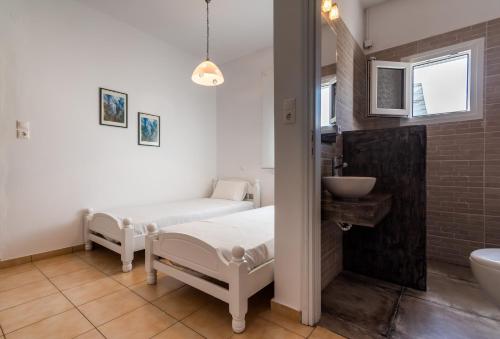 a bathroom with two white beds and a sink at Iliopoulou Studios in Pollonia