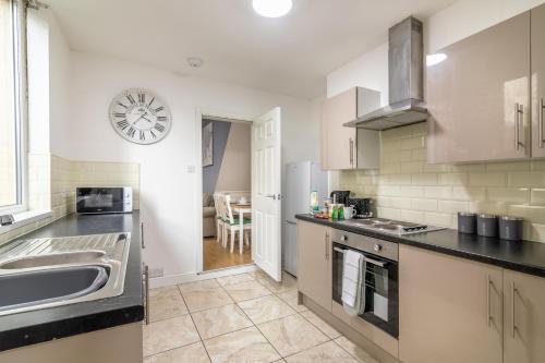 uma cozinha com um lavatório e um relógio na parede em PLATFORM Fishing Quarter Apartment 1 em Hull