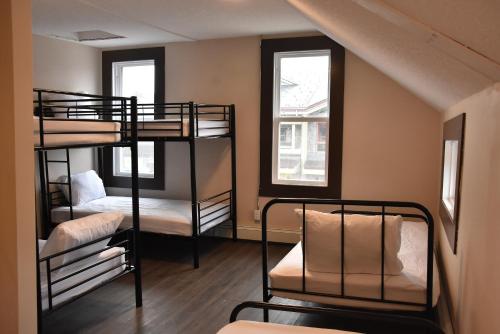 two bunk beds in a room with two windows at PARTY HOSTEL - The Canmore Hotel Hostel in Canmore