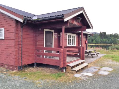une cabane rouge avec une terrasse et une table de pique-nique dans l'établissement Harran Camping, à Grong
