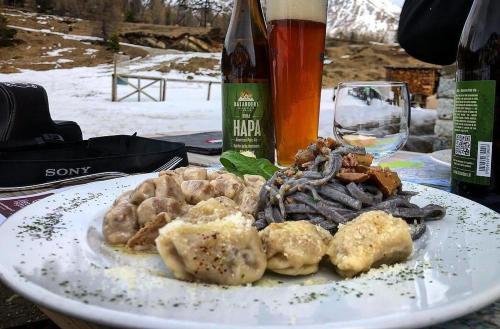 a plate of food on a table with a glass of wine at RIFUGIO AL LAGO DEL MORTIROLO in inverno raggiungibile solo a piedi in Monno