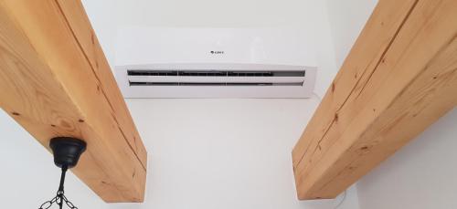 a white air conditioner in a room with wooden ceilings at Bungalows Michalka - Podhájska in Podhájska