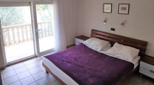 a bedroom with a bed with a purple blanket at VILLA PUNTA BLAVA - beach front, ideal for kids, large terraces with sea view, internet, Netflix, no pets allowed, 3Kw EV ch in Obrovac