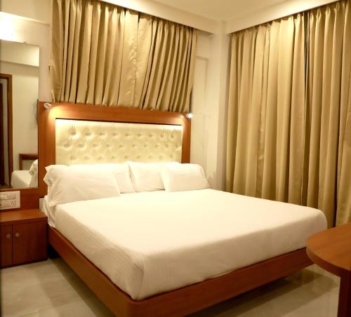 a bedroom with a large bed with white sheets at Hotel Lords, Fort in Mumbai