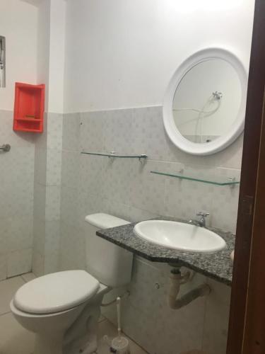 a bathroom with a toilet and a sink and a mirror at Flat Shopping Amarração N - 129 in Luis Correia