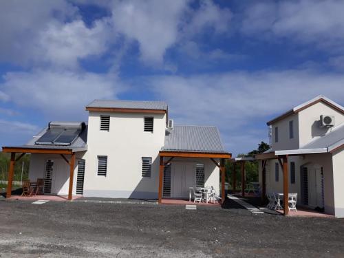 ein weißes Haus mit schwarzen Fensterläden in der Unterkunft KAZ's à l'Anse Maurice in Gros Cap