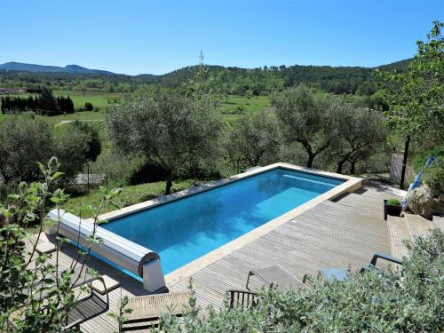 a swimming pool in a garden with a wooden deck at O PATIO DU MAS in Callas