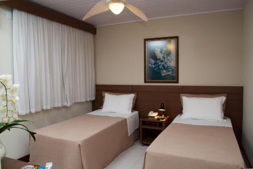 ジョインヴィレにあるPríncipe Hotelのベッド2台が備わる部屋、壁に絵が飾られた部屋