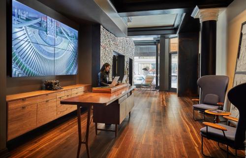 a woman sitting at a desk in a room with a tv at Hotel Emblem San Francisco in San Francisco