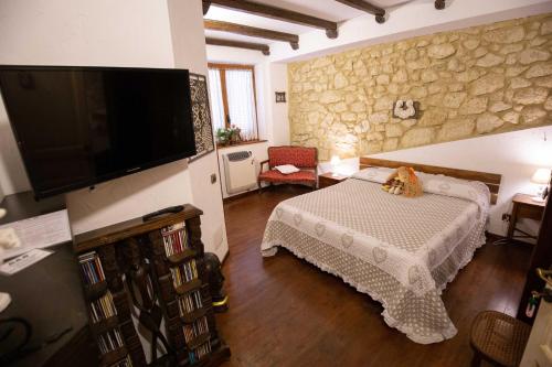a bedroom with a bed and a tv on a wall at La Casa In Pietra in Santa Caterina Villarmosa