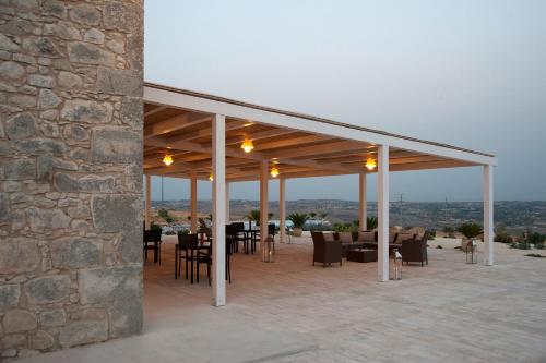 a patio with tables and chairs and a stone wall at La Dimora di Spartivento - BW Signature Collection in Ragusa
