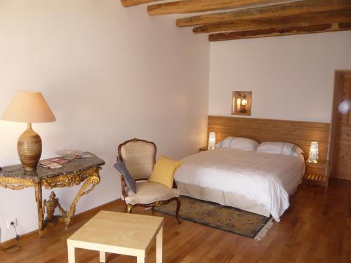 a bedroom with a bed and a chair and a table at La Thibaude - Livry in Livry