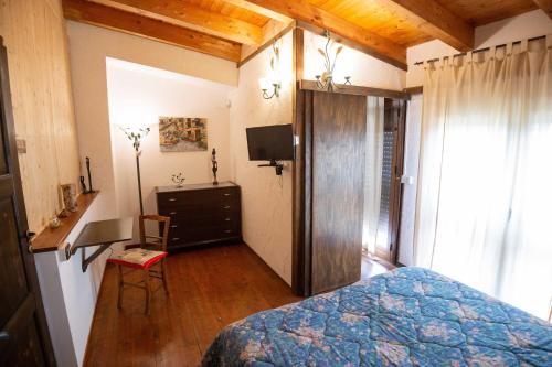 a bedroom with a bed and a desk and a television at La Casa In Pietra in Santa Caterina Villarmosa