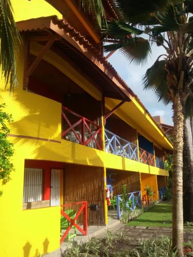 a yellow building with a palm tree in front of it at Pousada Recanto do Sossego in Itamaracá